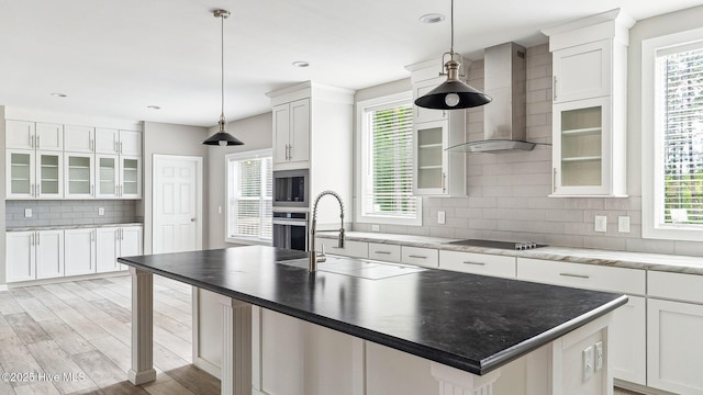 290 Boulder Dr, West End, NC 27376 - kitchen featuring wall chimney range hood, a sink, appliances with stainless steel finishes, tasteful backsplash, and glass insert cabinets