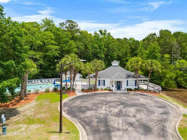 280 Coralstone Ct, Leland, NC 28451 - view of front of home featuring curved driveway, a forest view, a shingled roof, and a community pool