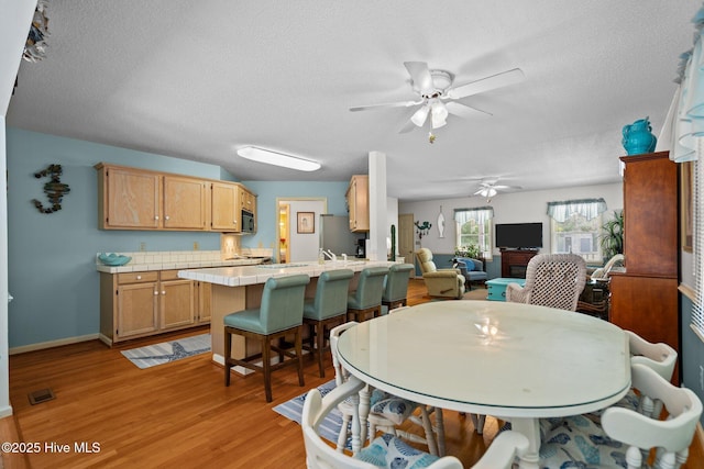 109 NE 1st St, Oak Island, NC 28465 - dining room featuring ceiling fan, light wood-style flooring, a textured ceiling, and baseboards