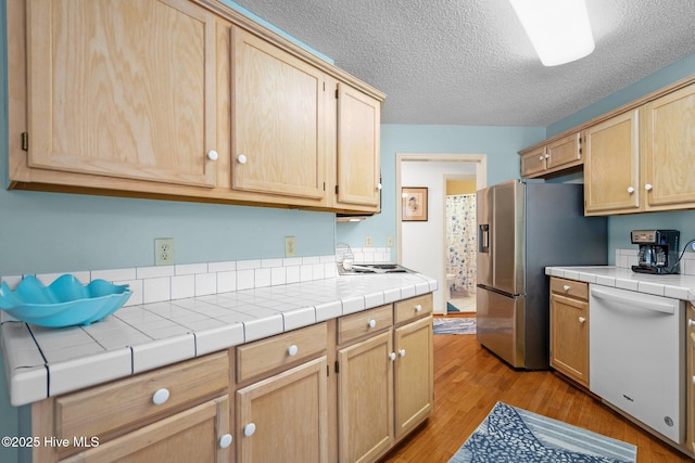 109 NE 1st St, Oak Island, NC 28465 - kitchen featuring dishwasher, stainless steel refrigerator with ice dispenser, light brown cabinetry, light wood finished floors, and a textured ceiling