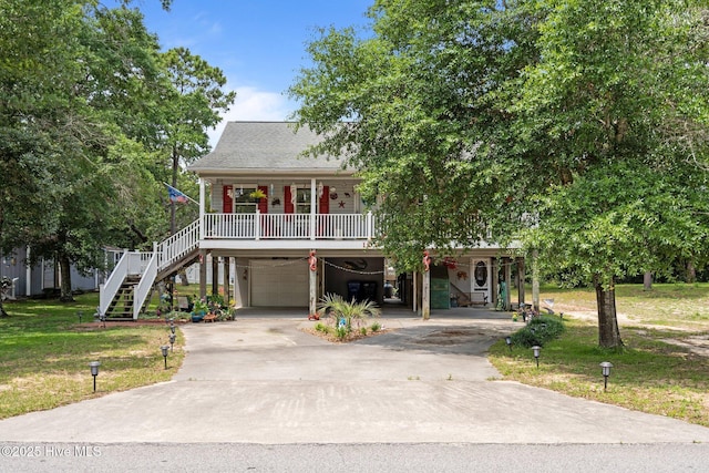 109 NE 1st St, Oak Island, NC 28465 - raised beach house with concrete driveway, a porch, a carport, stairway, and a front lawn