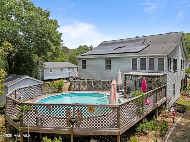 109 NE 1st St, Oak Island, NC 28465 - back of house featuring a wooden deck, roof mounted solar panels, and roof with shingles