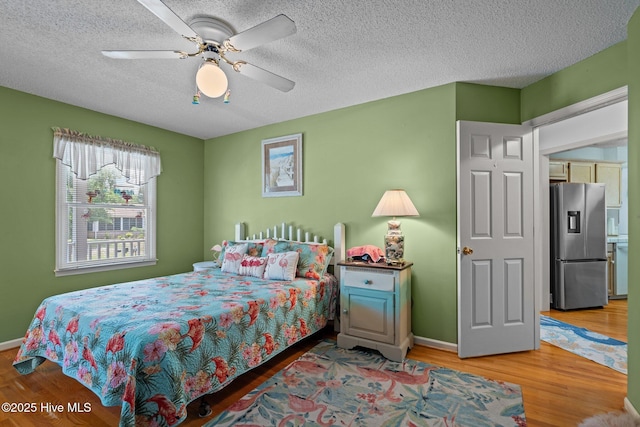 109 NE 1st St, Oak Island, NC 28465 - bedroom with stainless steel fridge, wood finished floors, a textured ceiling, baseboards, and a ceiling fan