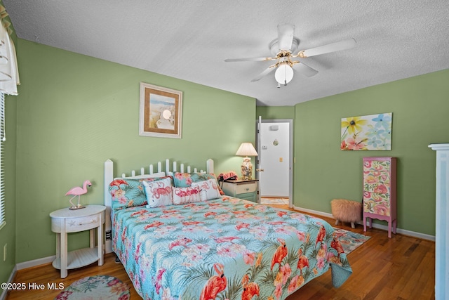 109 NE 1st St, Oak Island, NC 28465 - bedroom with wood finished floors, a textured ceiling, baseboards, and a ceiling fan