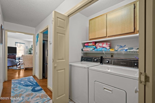 109 NE 1st St, Oak Island, NC 28465 - laundry room with cabinet space, light wood-style flooring, washer and clothes dryer, and a textured ceiling