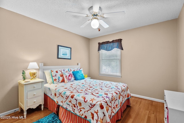 109 NE 1st St, Oak Island, NC 28465 - bedroom with baseboards, wood finished floors, a textured ceiling, and a ceiling fan