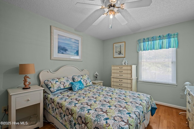 109 NE 1st St, Oak Island, NC 28465 - bedroom with a textured ceiling, wood finished floors, baseboards, and a ceiling fan