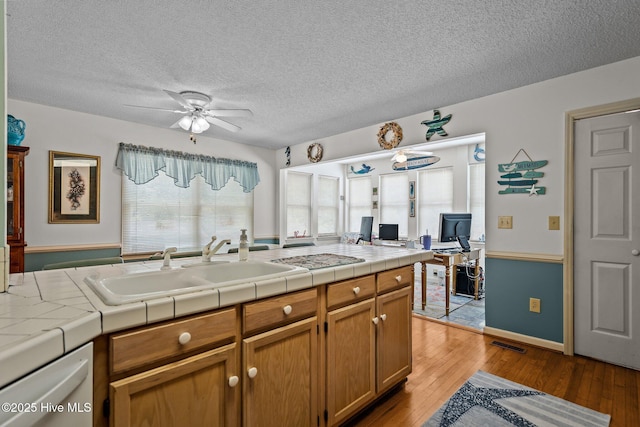 109 NE 1st St, Oak Island, NC 28465 - kitchen featuring a ceiling fan, dishwasher, a textured ceiling, a sink, and tile counters