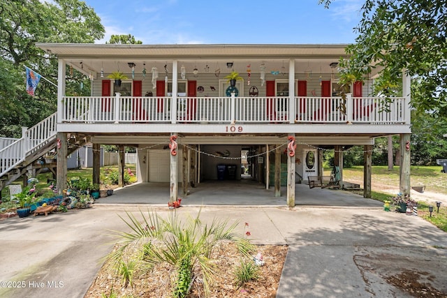 109 NE 1st St, Oak Island, NC 28465 - coastal home featuring concrete driveway, a carport, covered porch, a garage, and stairway