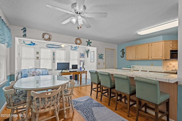 109 NE 1st St, Oak Island, NC 28465 - kitchen featuring tile countertops, light brown cabinetry, a textured ceiling, a peninsula, and an office area