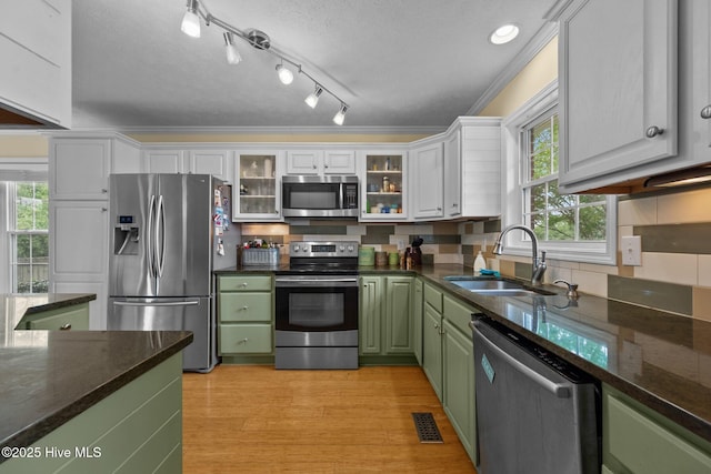 206 Lansing Ct, Jacksonville, NC 28540 - kitchen featuring appliances with stainless steel finishes, green cabinetry, a sink, white cabinets, and backsplash