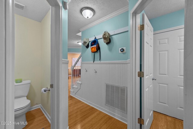 206 Lansing Ct, Jacksonville, NC 28540 - bathroom with a textured ceiling, wood finished floors, toilet, wainscoting, and ornamental molding