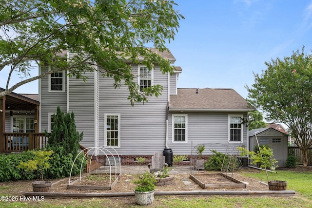 206 Lansing Ct, Jacksonville, NC 28540 - back of property with a vegetable garden, central air condition unit, a shingled roof, and a yard