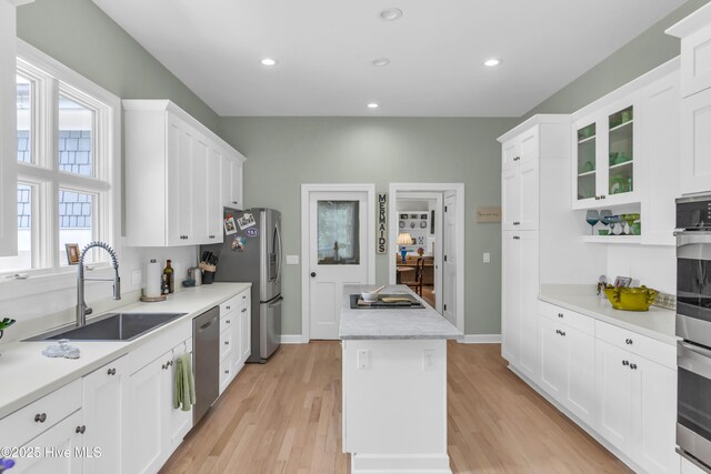 2021 Seawind Ln, Wilmington, NC 28405 - kitchen featuring a sink, appliances with stainless steel finishes, a center island, light wood-style floors, and white cabinetry