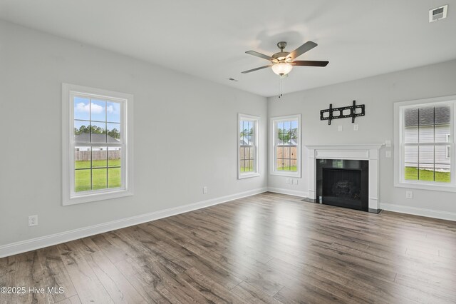 33 Chippewa Ln, Rocky Point, NC 28457 - unfurnished living room featuring plenty of natural light, wood finished floors, a fireplace with flush hearth, and baseboards