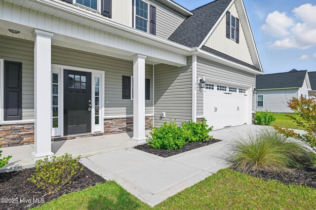 33 Chippewa Ln, Rocky Point, NC 28457 - property entrance featuring a porch, stone siding, an attached garage, and roof with shingles