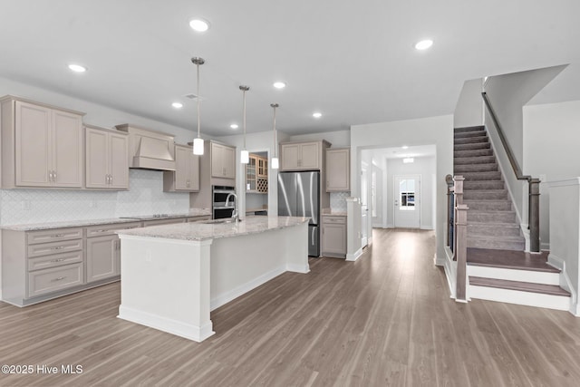 81 Eagle Claw Dr, Calabash, NC 28467 - kitchen with appliances with stainless steel finishes, light wood finished floors, tasteful backsplash, a sink, and an island with sink