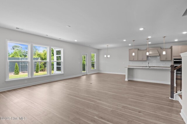 81 Eagle Claw Dr, Calabash, NC 28467 - unfurnished living room featuring stairway, recessed lighting, baseboards, light wood finished floors, and a sink