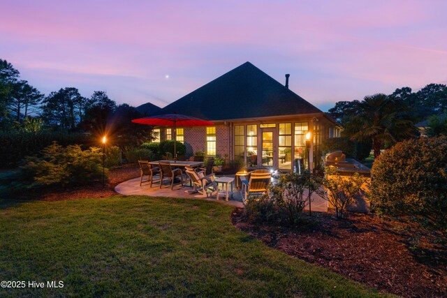 310 White Swan Ct, Wilmington, NC 28412 - back of property at dusk with area for grilling, a patio area, and a lawn