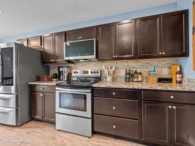 660 Riggs Rd, Hubert, NC 28539 - kitchen with appliances with stainless steel finishes, dark brown cabinetry, backsplash, light wood-type flooring, and light stone counters