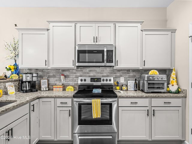 2 Catalina Cir, Swansboro, NC 28584 - kitchen featuring appliances with stainless steel finishes, backsplash, light stone counters, and white cabinetry