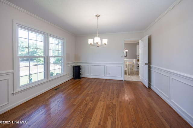 202 Forest Dr, Clinton, NC 28328 - unfurnished dining area with a chandelier, healthy amount of natural light, wood finished floors, a decorative wall, and ornamental molding