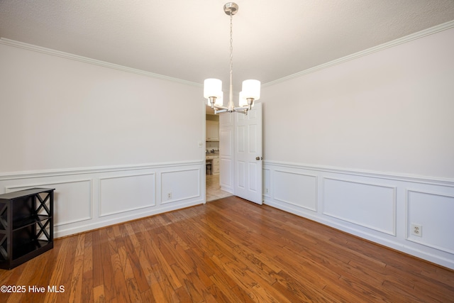 202 Forest Dr, Clinton, NC 28328 - spare room featuring a chandelier, crown molding, wood finished floors, wainscoting, and a decorative wall