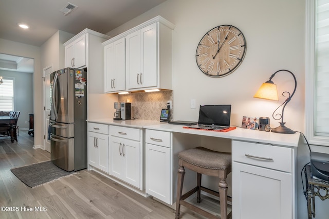 382 Sandy Brook Ct, Supply, NC 28462 - kitchen featuring freestanding refrigerator, light wood-type flooring, white cabinetry, decorative backsplash, and light countertops