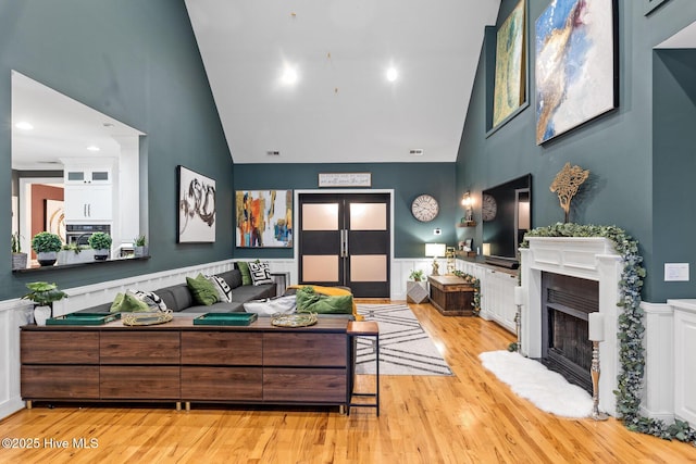 3108 Rivendell Pl, Wilmington, NC 28411 - living room featuring high vaulted ceiling, wainscoting, a fireplace with raised hearth, and light wood-type flooring
