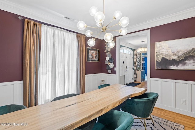 3108 Rivendell Pl, Wilmington, NC 28411 - dining room with a chandelier, wainscoting, ornamental molding, a decorative wall, and wood finished floors
