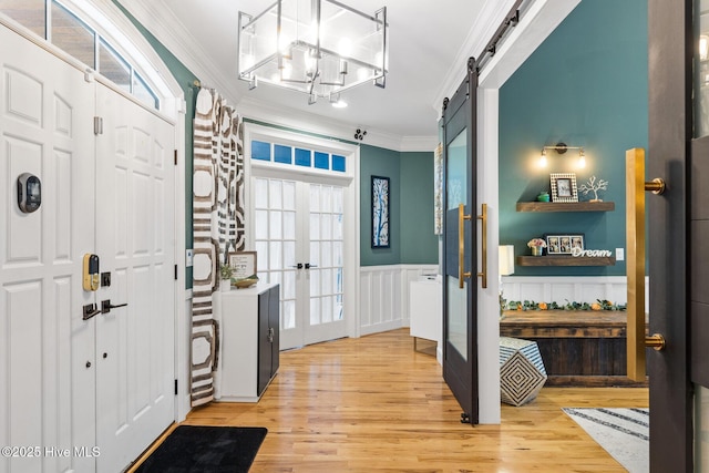 3108 Rivendell Pl, Wilmington, NC 28411 - foyer with ornamental molding, french doors, a barn door, light wood-type flooring, and wainscoting
