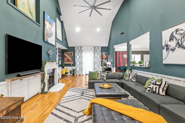 3108 Rivendell Pl, Wilmington, NC 28411 - living room featuring high vaulted ceiling, a fireplace, light wood finished floors, a ceiling fan, and wainscoting