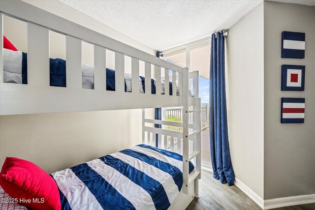 2000 New River Inlet Rd Unit 1208, North Topsail Beach, NC 28460 - bedroom featuring wood finished floors, a textured ceiling, and baseboards