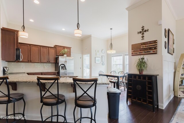 411 Canvasback Ln, Sneads Ferry, NC 28460 - kitchen with backsplash, a kitchen bar, light stone counters, decorative light fixtures, and crown molding