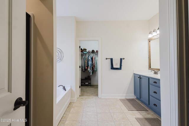 411 Canvasback Ln, Sneads Ferry, NC 28460 - bathroom with vanity, a bath, a spacious closet, tile patterned floors, and baseboards