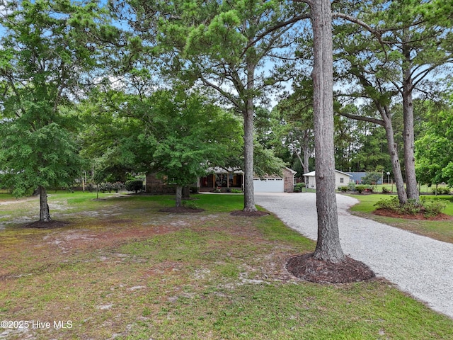 827 Village Point Rd SW, Shallotte, NC 28470 - view of property hidden behind natural elements with a front lawn, a garage, and gravel driveway