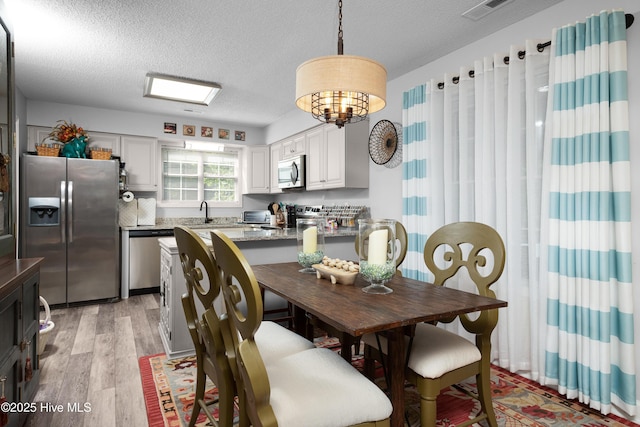229 Trappers Trl, New Bern, NC 28560 - dining space with a textured ceiling, light wood-style floors, and a chandelier