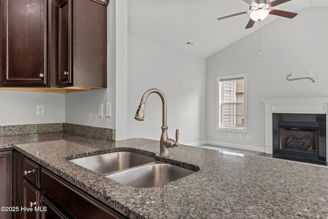 1005 Flounder Run, New Bern, NC 28562 - kitchen with a sink, ceiling fan, dark stone countertops, dark brown cabinetry, and a fireplace with flush hearth