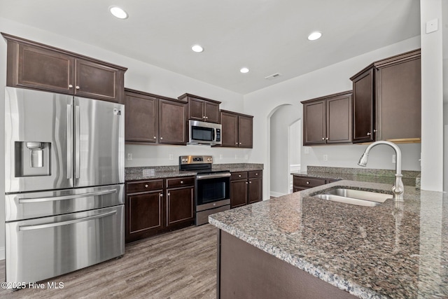 1005 Flounder Run, New Bern, NC 28562 - kitchen with stainless steel appliances, a sink, arched walkways, dark brown cabinets, and dark stone counters