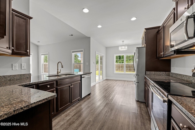 1005 Flounder Run, New Bern, NC 28562 - kitchen with appliances with stainless steel finishes, a sink, wood finished floors, dark brown cabinetry, and dark stone counters