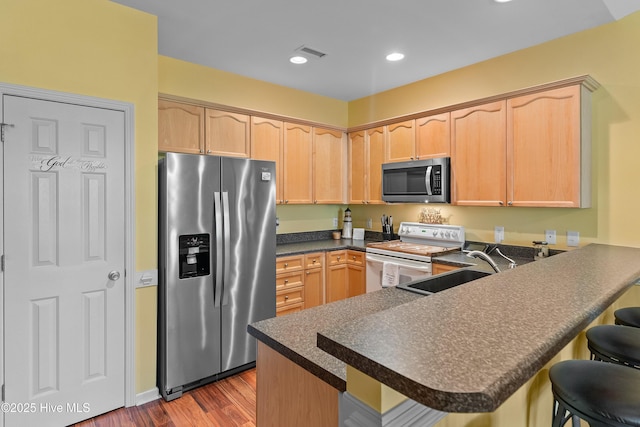 4256 Anderson Dr SE, Southport, NC 28461 - kitchen with appliances with stainless steel finishes, light brown cabinets, wood finished floors, a sink, and dark countertops
