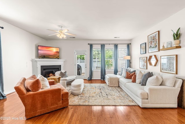 2635 Asher View Ct, Raleigh, NC 27606 - living room with a lit fireplace, ceiling fan, and wood finished floors