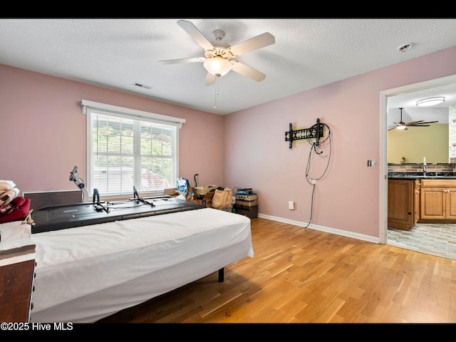 71 Combine Ln SE, Leland, NC 28451 - bedroom featuring light wood-type flooring, baseboards, a sink, a ceiling fan, and a textured ceiling