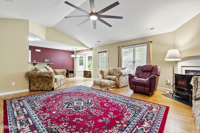 71 Combine Ln SE, Leland, NC 28451 - living area featuring a ceiling fan, a textured ceiling, wood finished floors, vaulted ceiling, and a wood stove