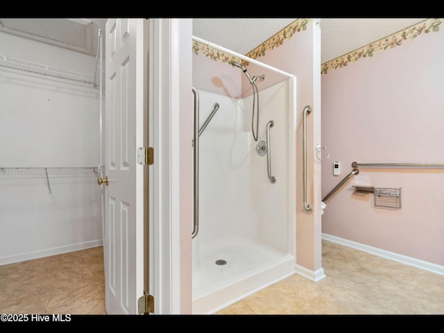71 Combine Ln SE, Leland, NC 28451 - bathroom with a stall shower, a walk in closet, baseboards, and a textured ceiling