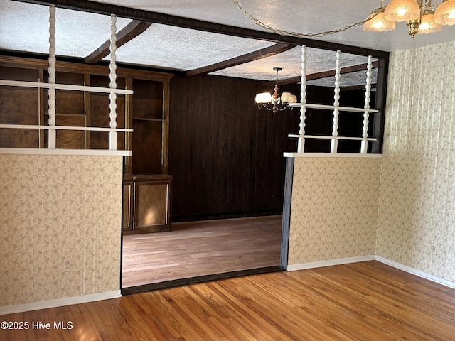 2611 Lisa Ln, Goldsboro, NC 27534 - spare room with a chandelier, wood finished floors, wallpapered walls, beam ceiling, and baseboards
