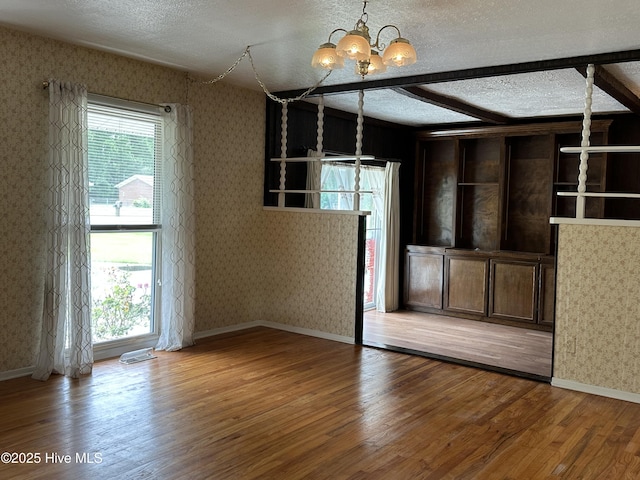 2611 Lisa Ln, Goldsboro, NC 27534 - spare room featuring a chandelier, wallpapered walls, a textured ceiling, wood finished floors, and baseboards
