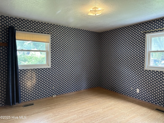2611 Lisa Ln, Goldsboro, NC 27534 - empty room featuring wallpapered walls, a textured ceiling, wood finished floors, and baseboards