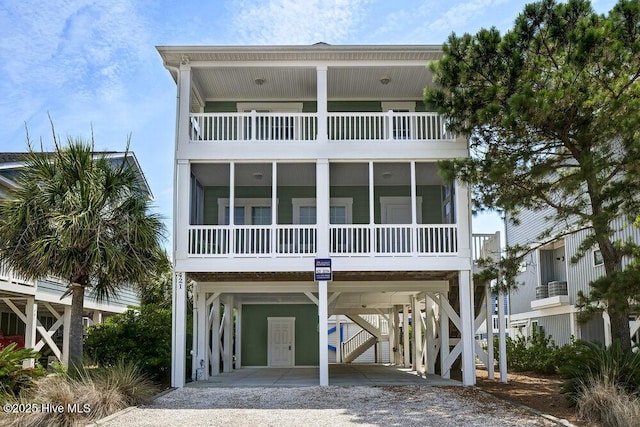 421 30th St, Sunset Beach, NC 28468 - beach home with a carport, gravel driveway, a balcony, and a sunroom