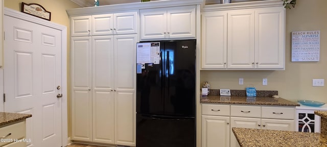 421 30th St, Sunset Beach, NC 28468 - kitchen with freestanding refrigerator, dark stone countertops, and white cabinets